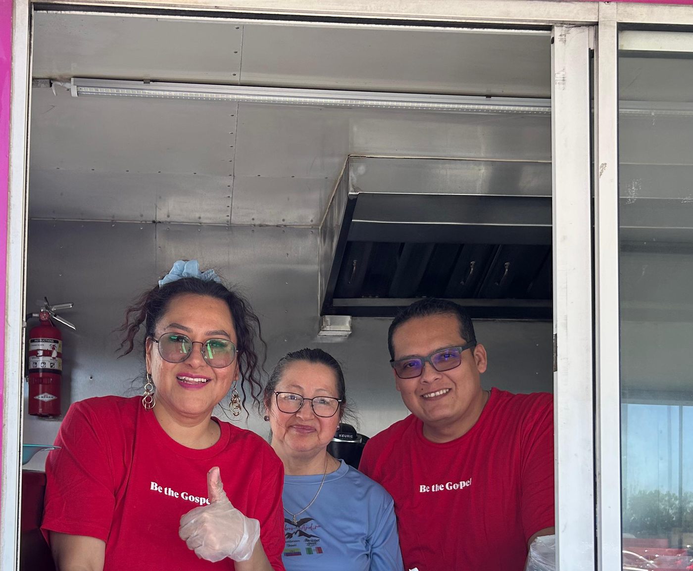 Voluntarios de i61 sonriendo desde un camión de comida
